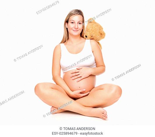 Portrait of a happy pregnant woman sitting on floor and holding belly
