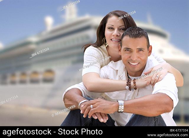 Young happy hispanic couple hugging on the dock in front of a cruise ship