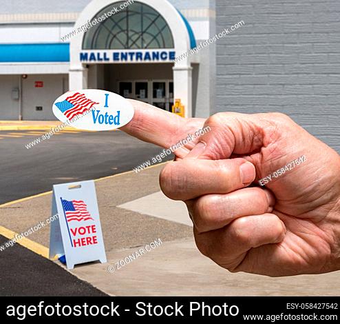 USA flag campaign button stuck to finger of voter by Polling place for early voting in the USA presidential elections