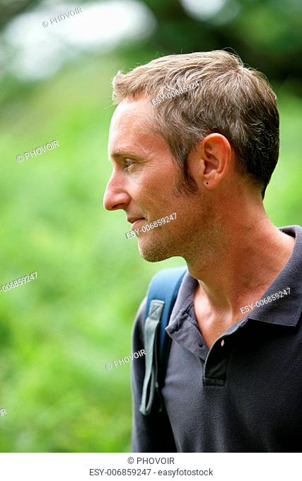 Man walking through the woods wearing backpack