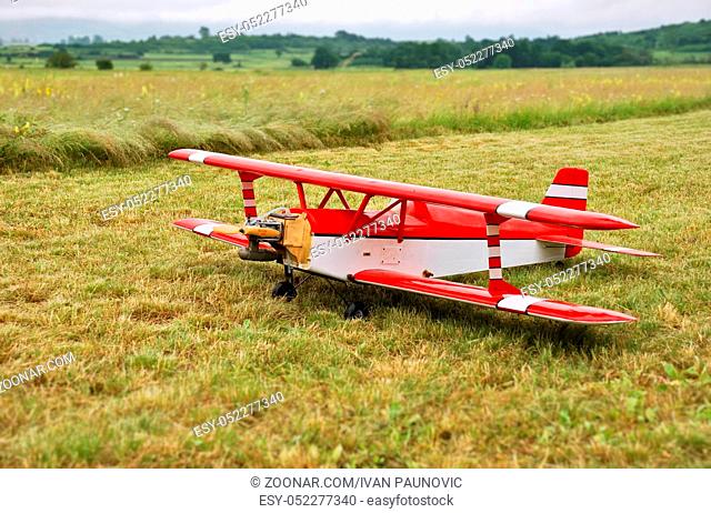 Red and white radio controlled aircraft with methanol engine on a grassy field