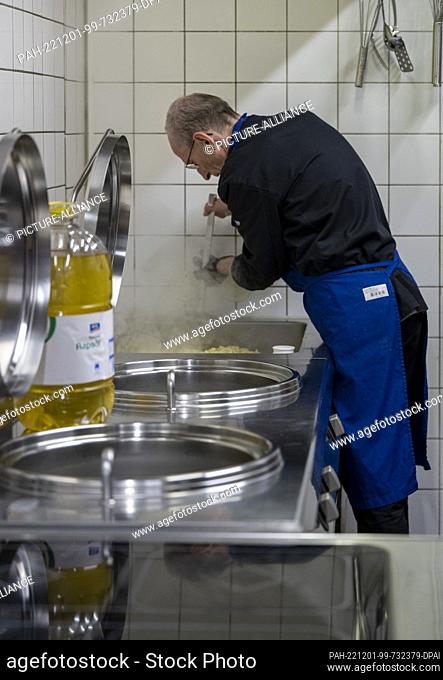 PRODUCTION - 28 November 2022, Berlin: An employee of the Berliner Stadtmission prepares a hot meal for homeless and needy people in the kitchen
