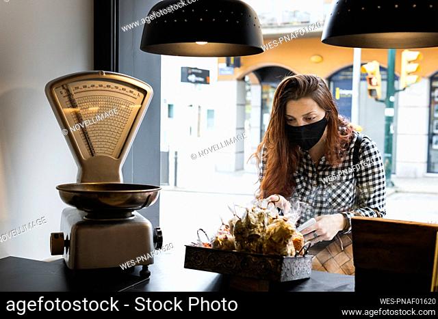 Woman wearing protective face mask taking food from counter at supermarket