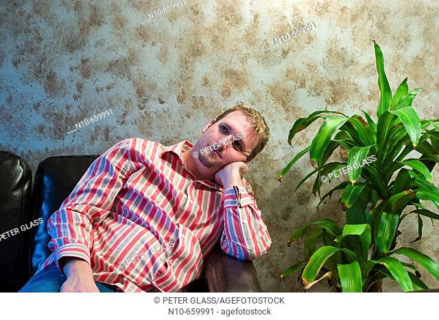 Young man sitting next to a plant