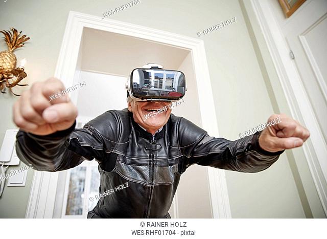 Senior man in motorcycle suit wearing VR glasses