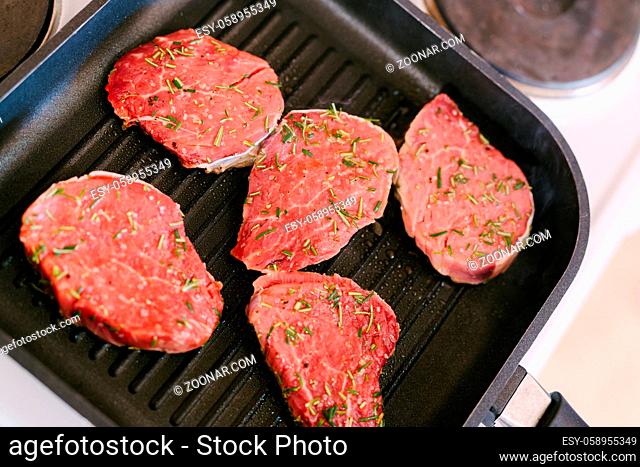 Four raw steaks are fried on a grilled pan. High quality photo
