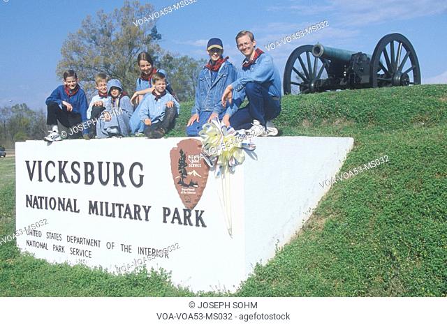 Family on sign on green grass at entrance of Vicksburg National Military Park, MS