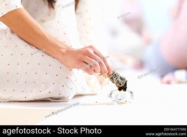 Woman lighting a smudge kit with herbal stick. Natural elements for cleansing environment from negative energy, adding positive vibes