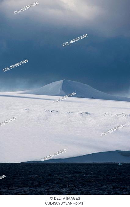 Snow covered coastal landscape with storm clouds, Hinlopen Strait, between Nordaustlandet and Spitsbergen, Svalbard, Norway