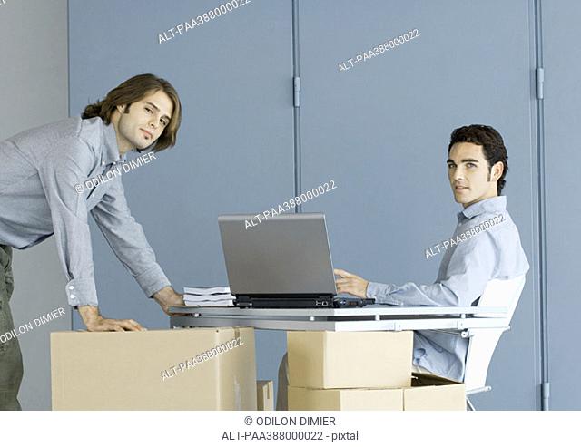 Businessmen working at table top supported by cardboard boxes