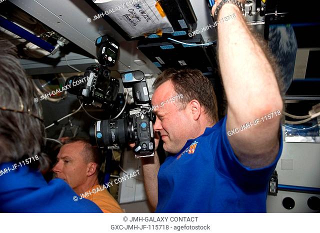 NASA astronaut Ron Garan, Expedition 27 flight engineer, uses a still camera in the Harmony node of the International Space Station shortly after space shuttle...