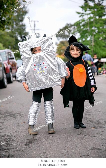 Portrait of boy in robot costume and girl in witch costume on street