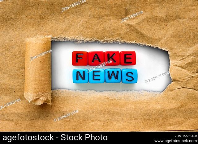 Brown package kraft paper torn to reveal Red & blue cubes with the words: fake news. Concept Fake News