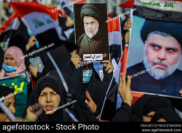 27 November 2020, Iraq, Baghdad: Supporters of Iraqi Shia cleric Muqtada al-Sadr hold his photos as they takes part in a rally in support of him at Tahrir...