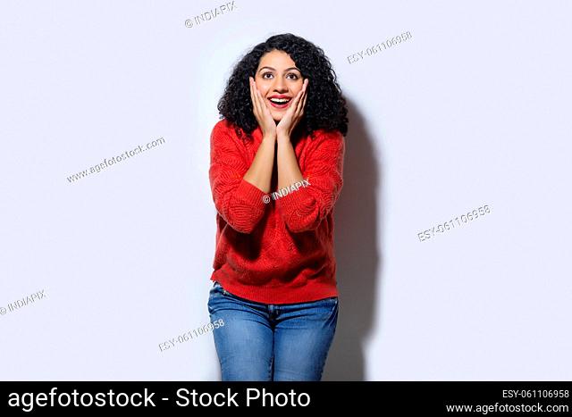 Young woman standing with holding her face in astonishment