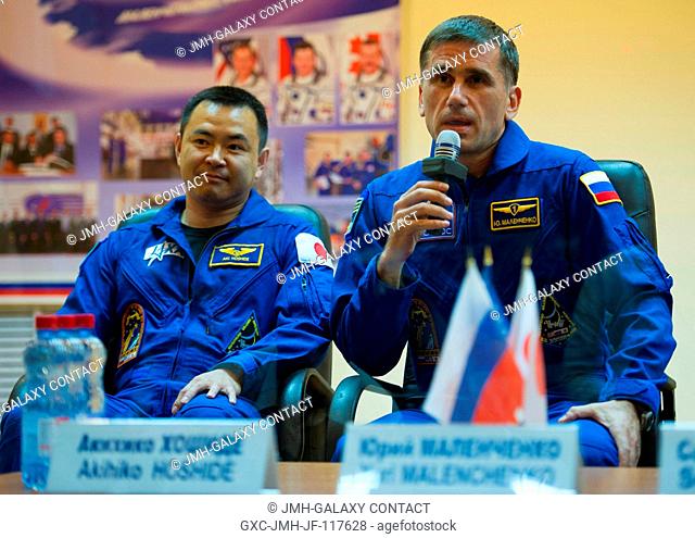 Quarantined Expedition 32 Soyuz Commander Yuri Malenchenko, right, answers reporters questions from behind glass during a prelaunch press conference held at the...