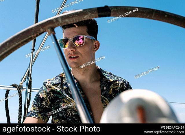 Handsome man seen through helm in yacht during summer