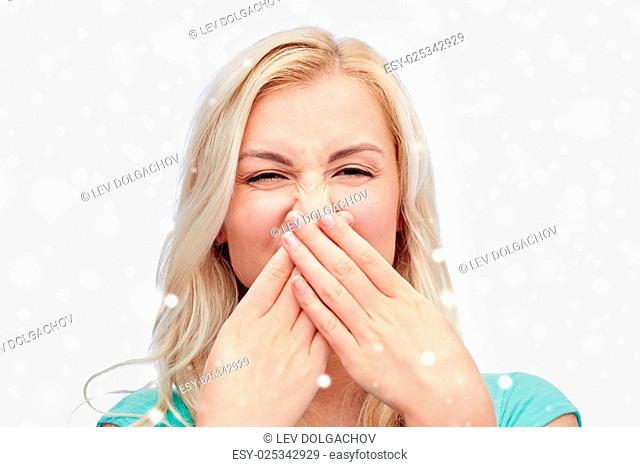 emotions, expressions, embarrassment, and people concept - young woman or teenage girl wrinkling and closing her nose of unpleasant smell over snow