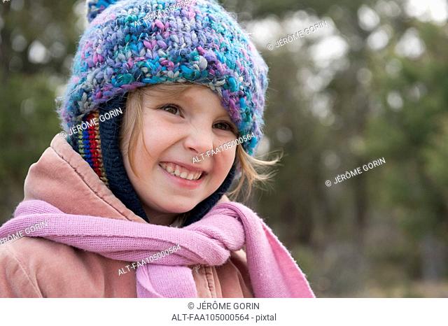 Little girl wearing knit hat and scarf, smiling, portrait