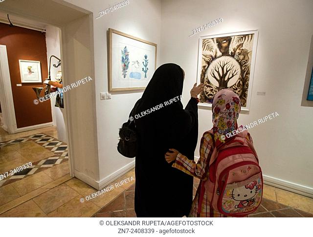 Young woman in traditional Muslim clothes discuss contemporary painting with her daughter during 2nd Grand Festival of Art for Peace in Tehran, Iran