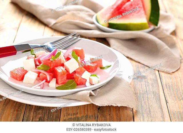 Watermelon salad with feta, mint and red onion. On wooden rustic table
