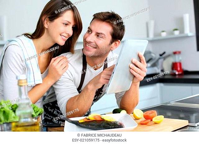 Couple in home kitchen using electronic tablet