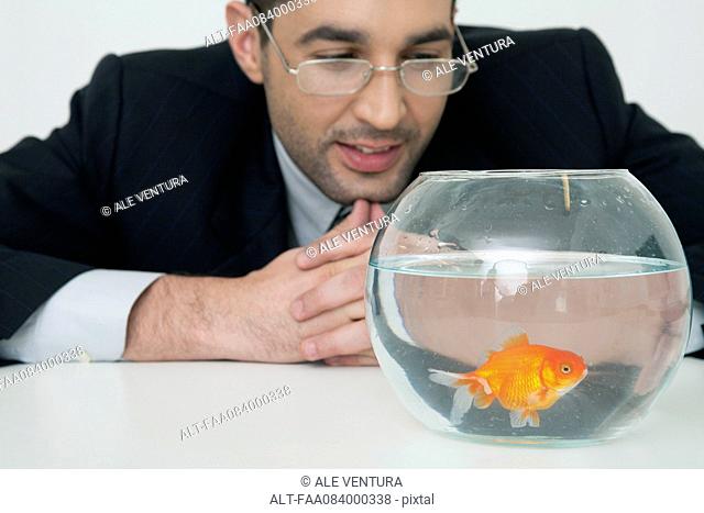 Mid-adult businessman watching goldfish in fishbowl