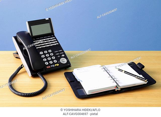 Telephone and agenda on wooden desk