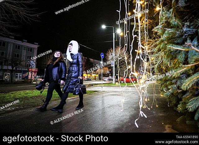 RUSSIA, LUGANSK - 20 DE DICIEMBRE, 2023: Las mujeres pasean por las decoraciones navideñas que brillan en la calle Sovetskaya. Alexander Reka/TASS