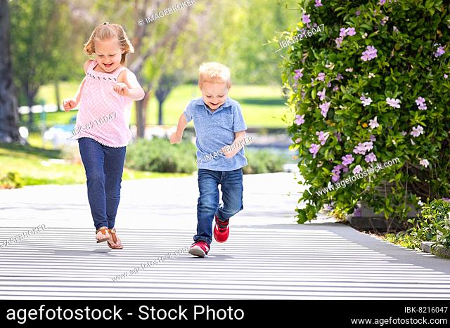 Young sister and brother having fun running at the park