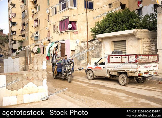 13 November 2022, Egypt, Alexandria: Two men are riding a motorized three-wheeled vehicle on a dirt road. Photo: Christophe Gateau/dpa