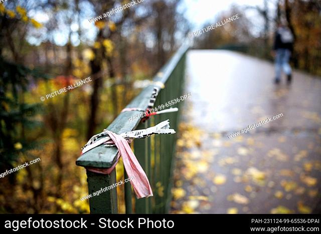24 November 2023, Bavaria, Munich: The remains of a police cordon can be seen on a railing on a pedestrian bridge on the Mittlerer Ring near the English Garden