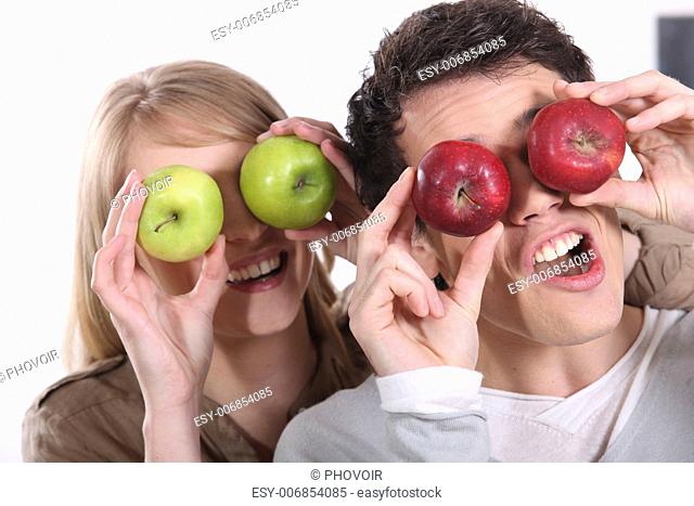 Couple pulling silly faces with apples