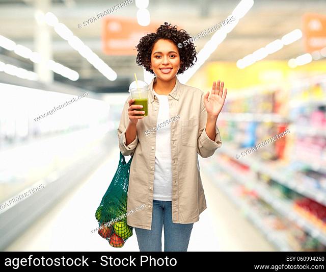 woman with reusable shopping bag drinking smoothie