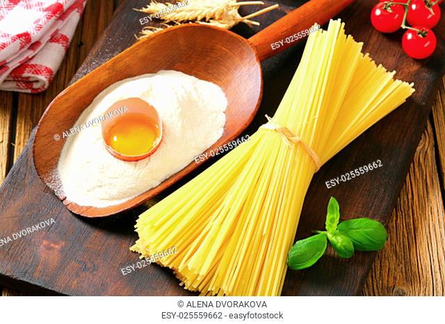 Bundle of dried spaghetti, scoop of flour and fresh egg