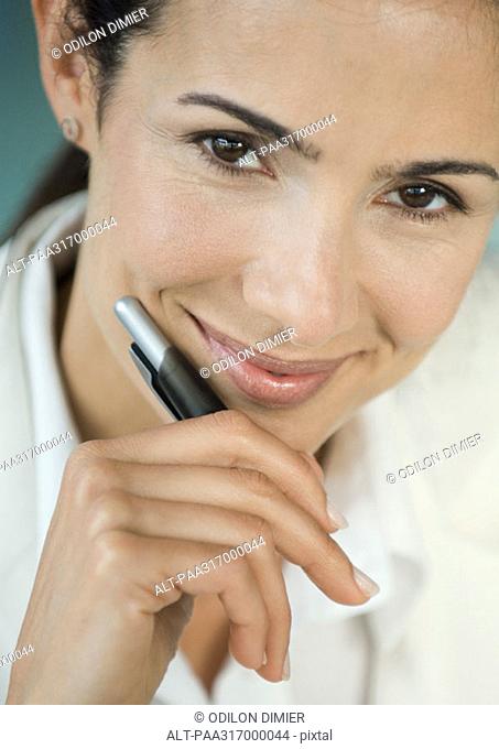 Businesswoman holding pen, smiling, portrait