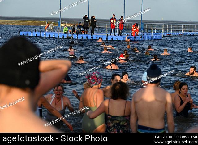 01 January 2023, Lower Saxony, Butjadingen: Many swimmers dare to jump into the cold water. A jump into the cold North Sea waves tempts many holidaymakers and...