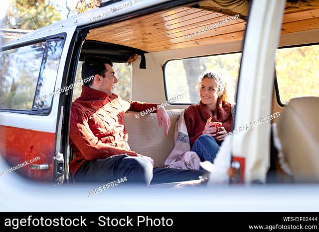 Smiling couple talking in campervan on weekend
