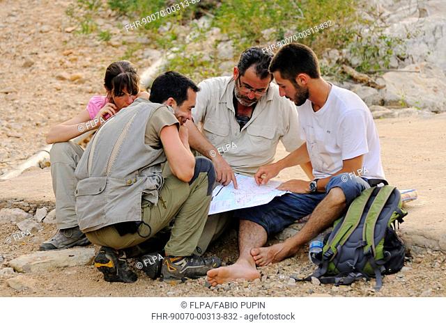 Researchers looking at map in desert, Socotra, Yemen, march