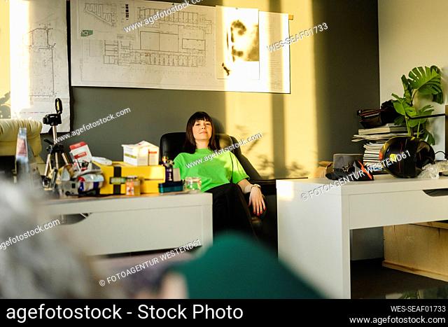 Woman leaning back in architect's office