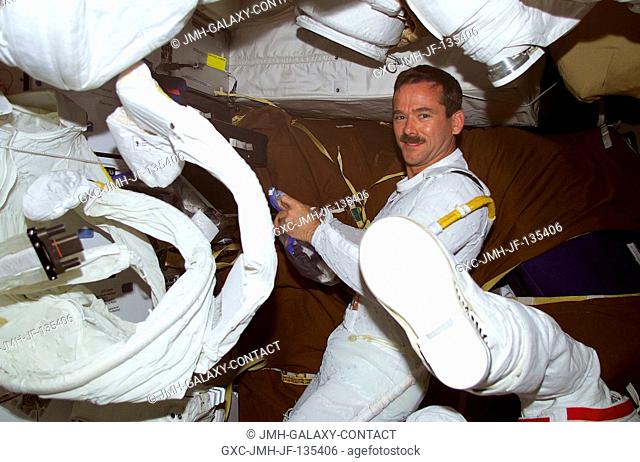 Astronaut Chris A. Hadfield, STS-100 mission specialist representing the Canadian Space Agency (CSA), dons his extravehicular mobility unit (EMU) space suit...