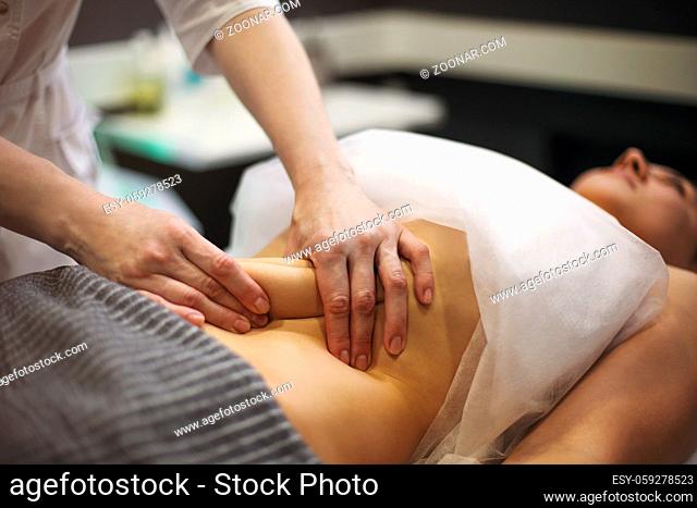 Partial view of masseur doing stomach massage to female on massage table