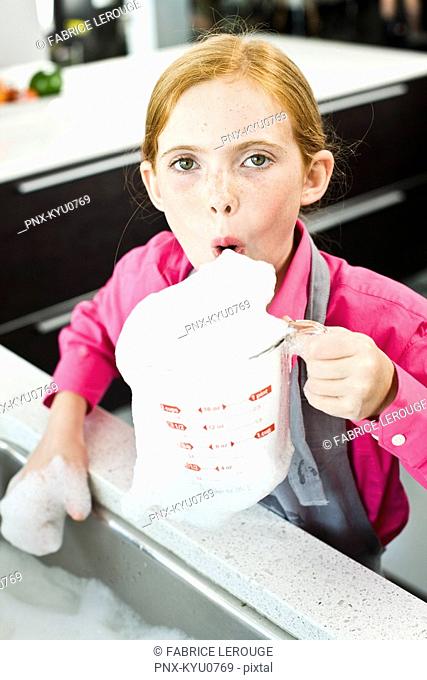 Portrait of a girl blowing soap suds in a measuring jug