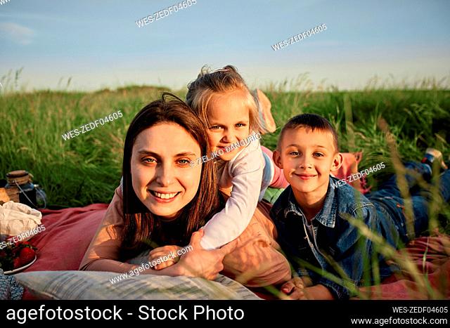 Smiling mother and children lying in field at picnic