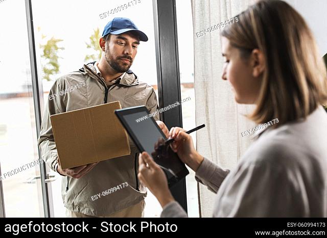 delivery man with box and woman signs digital form