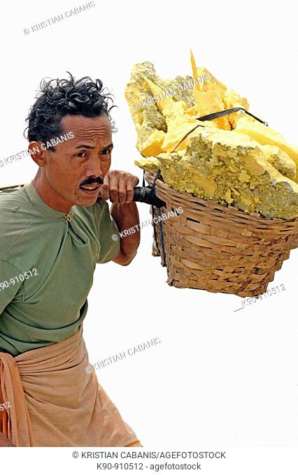 Half body shot of worker carrying wicker baskets on his shoulder filled with yellow slices of sulphur, Kawah Ijen Volcano, East Java, Indonesia, Southeast Asia