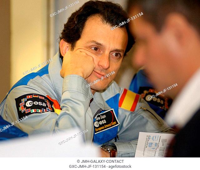 European Space Agency (ESA) astronaut Pedro Duque of Spain listens to a briefing on mission activities from a Russian trainer at his crew quarters in Baikonur