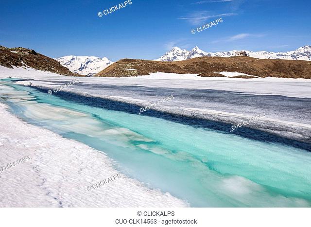 The crystal clear waters of Lake Emet are revealed to thaw, in the background the snow covered peaks, Madesimo, Chiavenna Valley, Spluga Valley, Valtellina