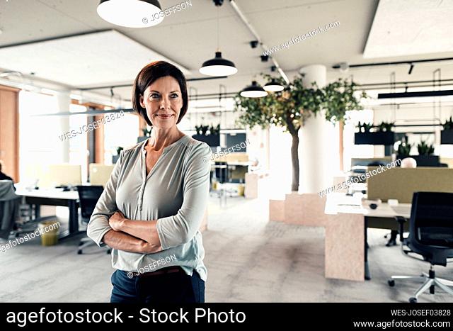 Confident businesswoman with arms crossed looking in office