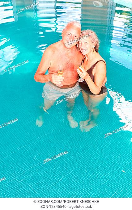 Glückliches verliebtes Senioren Paar mit einem Glas Sekt im Swimmingpool